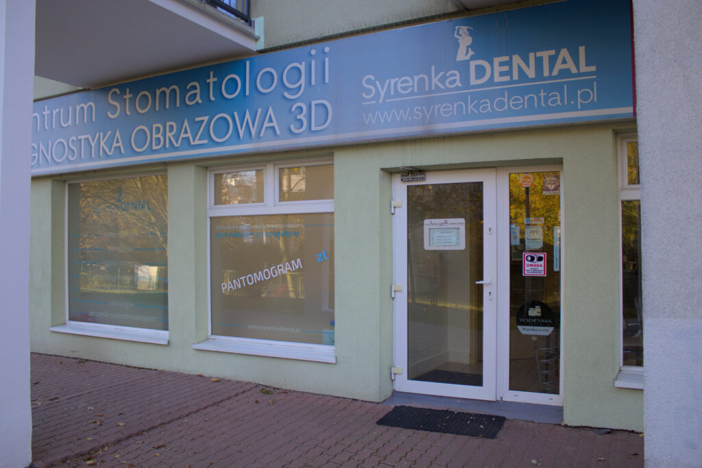 Wejście do kliniki Syrenka Dental z nazwą kliniki i oferowanymi usługami, takimi jak obrazowanie diagnostyczne 3D, podkreślone przez czystą i profesjonalną fasadę